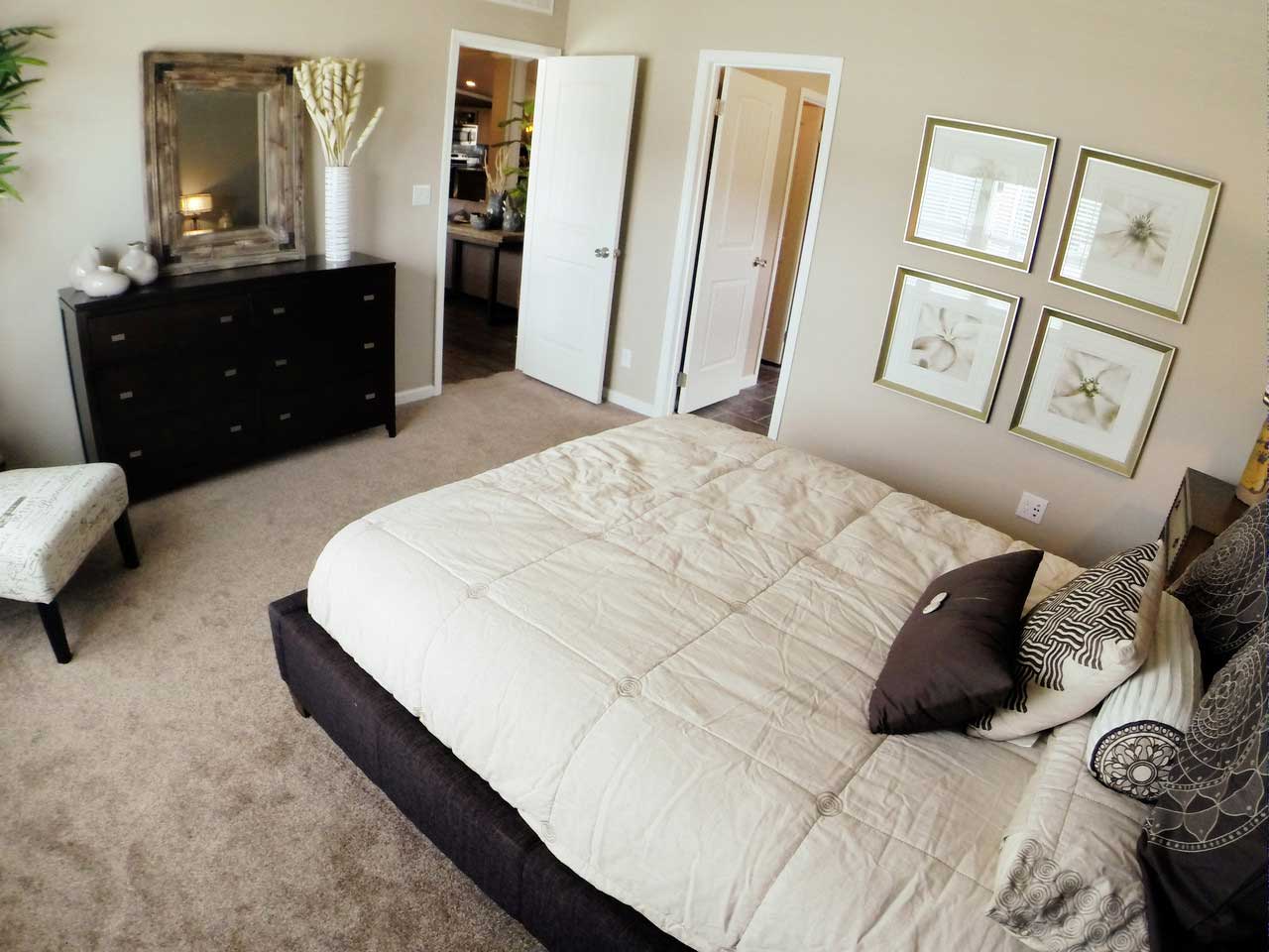 Cozy and inviting, this bedroom features a white queen sized bed, soft carpet flooring, and a stylish dresser for all your storage needs.