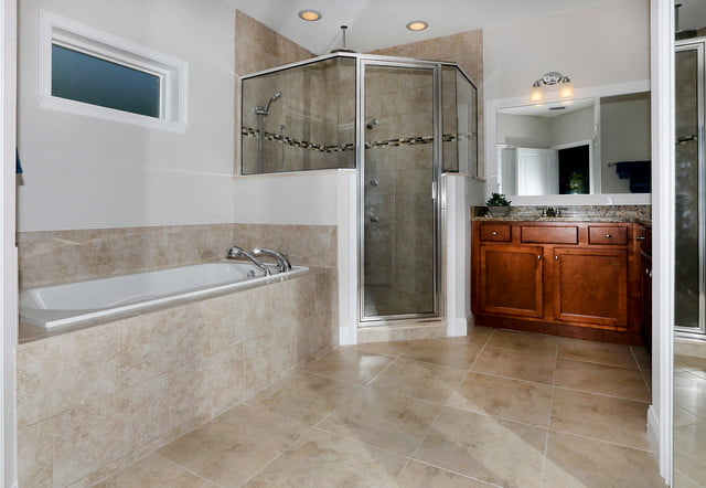 The bathroom is spacious and modern, with a large bathtub situated next to the shower room. The sink and mirror are located beside the shower, providing plenty of space for getting ready in the morning.