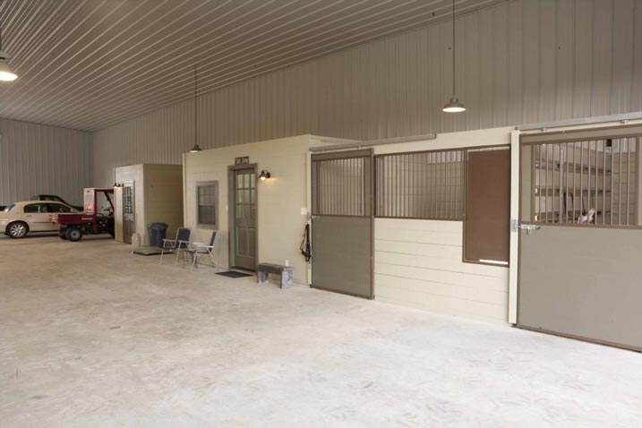 This image shows horse stables located inside a garage, complete with stalls for the animals and all the necessary equipment for their care..