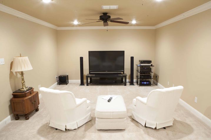 An entertainment room with chairs and an ottoman, a TV as a centerpiece.