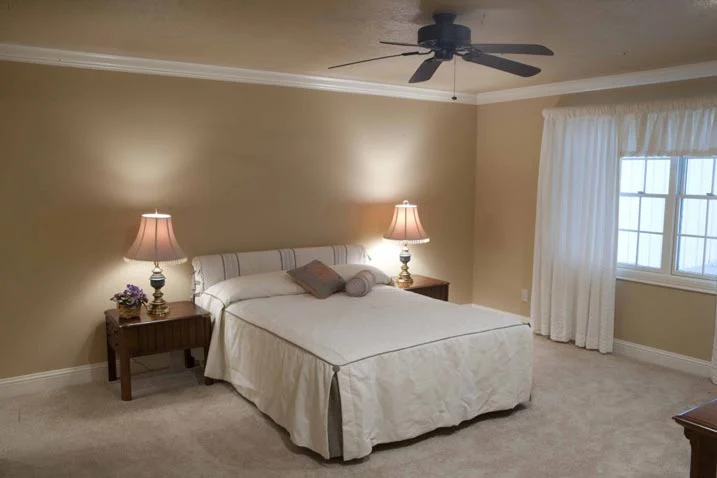 This inviting and cozy room features a white queen size bed, with night stands and lamps on its side.