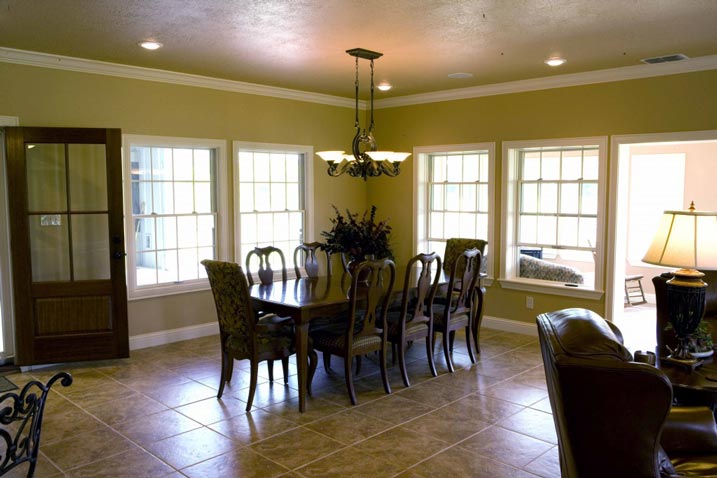 This dining room features a complete table set for 6 people, and is well-lit with large windows.