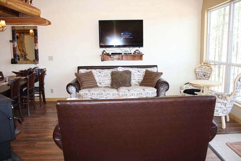 The living room is furnished with sofas, chairs, table, and a wall mounted TV