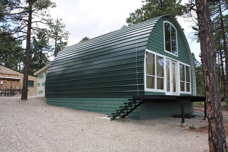 The front-left view of the Arched Metal Cabin, emphasizing its arched shape and lovely exterior color.