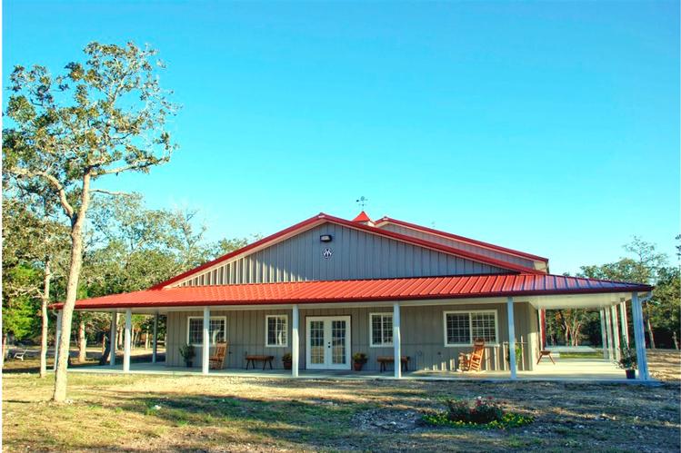 The front view shot of the metal barndominium with a red roof and neutral grey walls. The red roof stands out against the grey walls, creating a visually striking contrast.