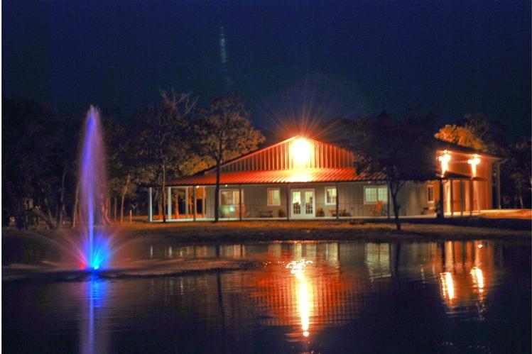This nighttime shot captures the peaceful beauty of a metal building home nestled beside a tranquil pond.