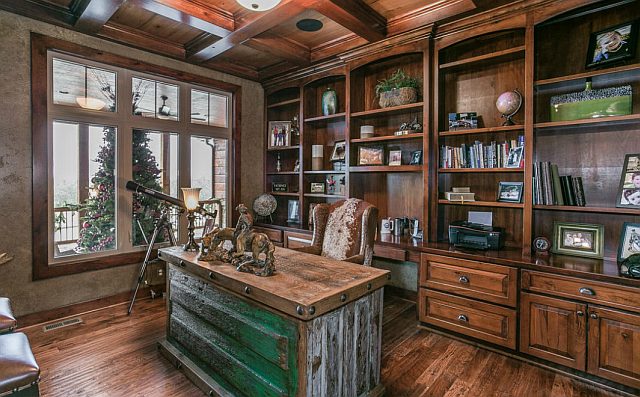 This cozy office features rustic cabinets and a desk with a comfortable chair placed in front of a window, creating the perfect space for productivity and relaxation.