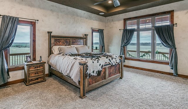 This cozy bedroom features a large bed with plush carpet flooring and windows that let in plenty of natural light. It's the perfect space for a restful night's sleep.