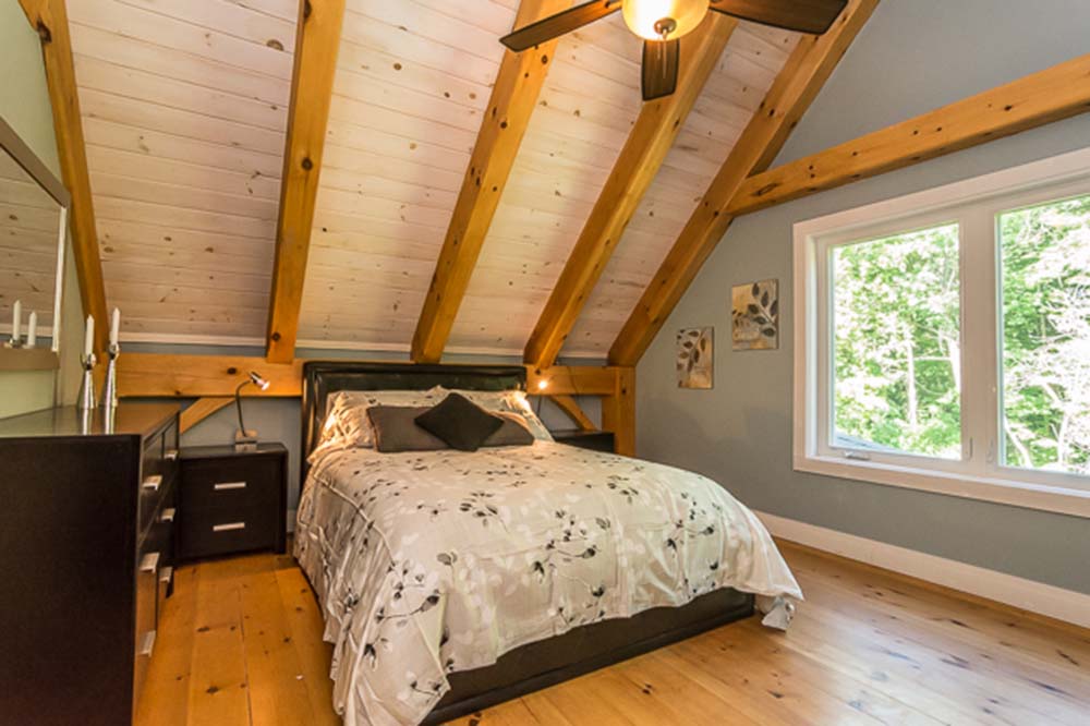 This cozy bedroom features dressers and a beautiful beamed ceiling, creating a warm and inviting space to relax in.