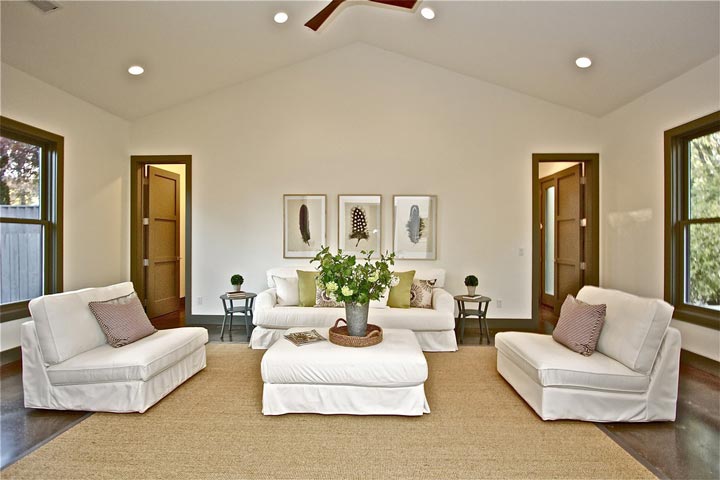 The living room features white sofas and ottoman on the center, sitting on a comfortable rug.