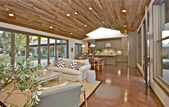 The hardwood ceiling adds warmth and character to the room, while the smooth tile flooring provides a clean and contemporary look. Natural light pours in through the windows, highlighting the space and enhancing the ambiance with the help of ceiling lights.