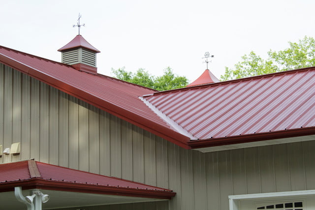 The bright red roof of the house features both gable and valley designs, adding visual interest to the exterior.