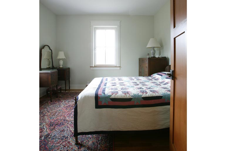 This warm and inviting bedroom features a white bed with a cozy comforter, a vibrant red rug, and a stylish dresser.