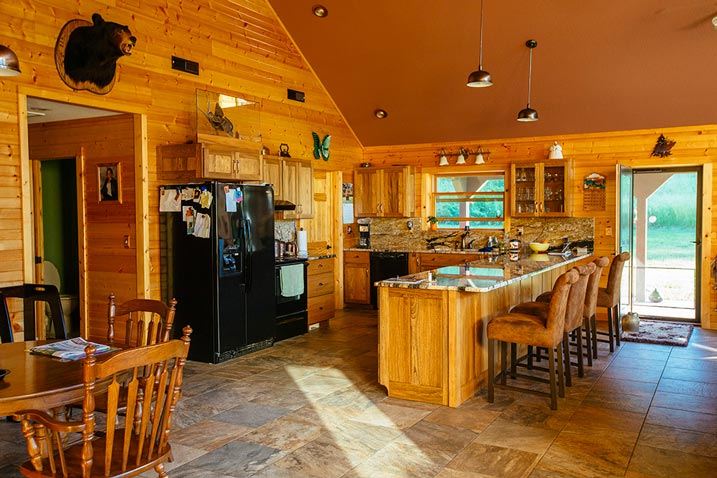 This kitchen features beautiful wooden cabinets and a spacious island bar with room for four bar stools. The warm, natural tones of the wood create a cozy and welcoming atmosphere.
