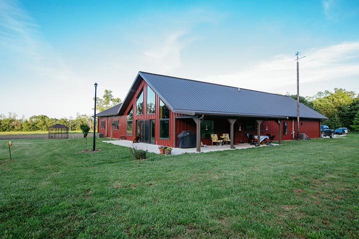 This metal building home boasts a bold exterior, with striking red walls and a dark roof. The combination of these contrasting colors creates a visually striking and modern look.