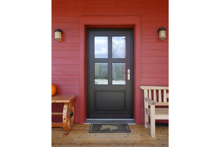 The door of the farmhouse has a black finish contrasting the bright red walls.