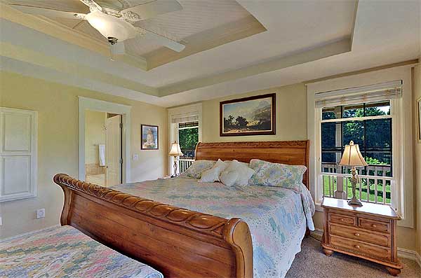 This bedroom boasts a spacious queen-sized bed and features two windows that allow natural light to flood the room. The elegant coffered ceiling adds a touch of sophistication to the space.