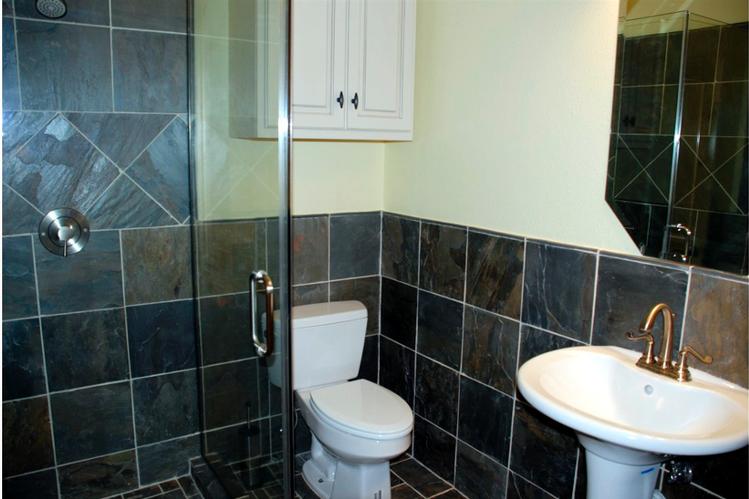 This image shows a bathroom with a toilet, tiled walls, and a shower. The shower is enclosed by a glass door, which allows for an open and spacious feel.