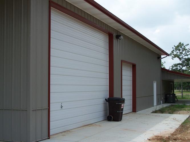 White garage Doors with red trim on the left side of the barndominium.