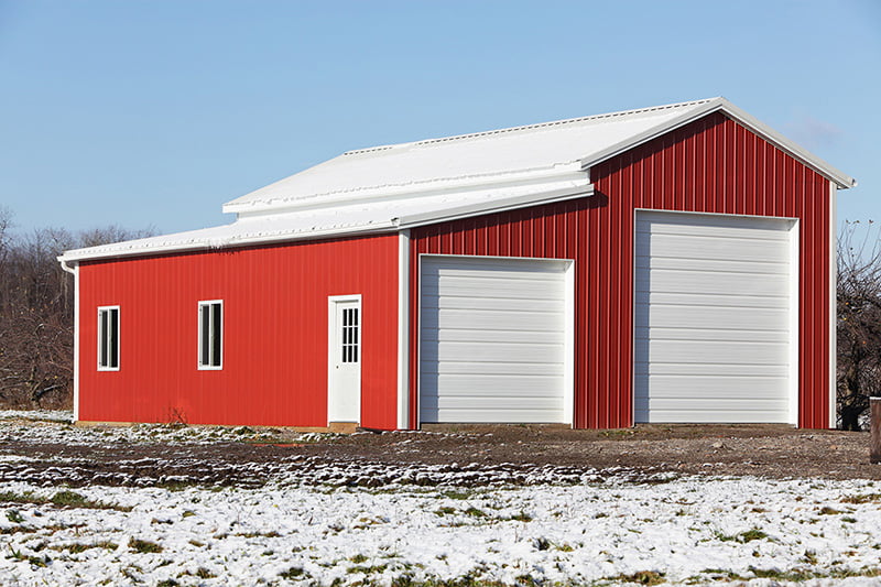 Red and white steel building barn with two garage doors erected by Elite Metal Buildings