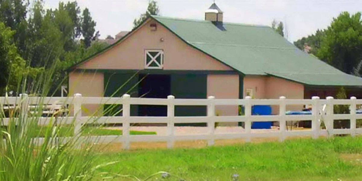 A large metal barn with sliding barn doors and a green gabled roof from General Steel Buildings