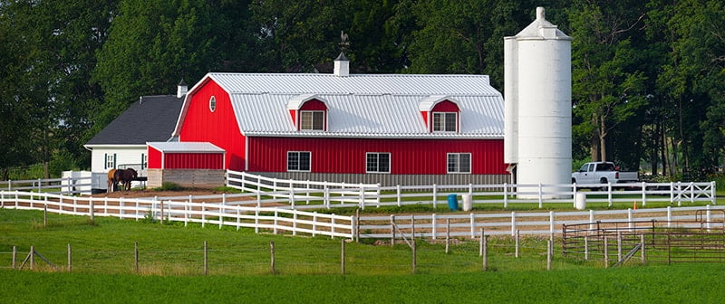 Red residential gambrel type metal building home with white roof erected by Elite Metal Buildings