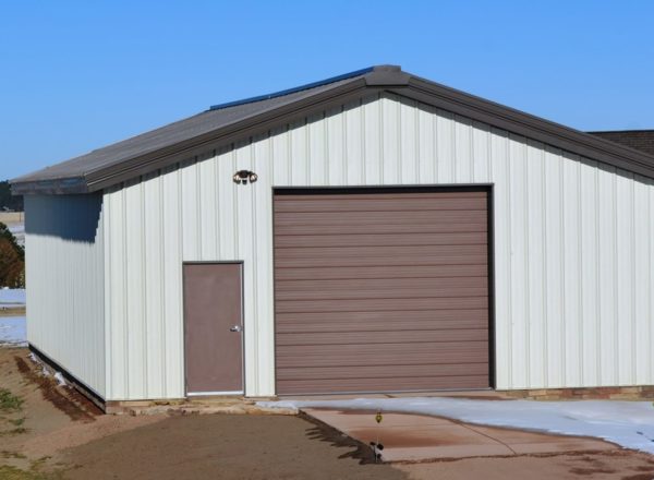 A large storage shed with gabled roof and brown sliding door from General Steel Buildings