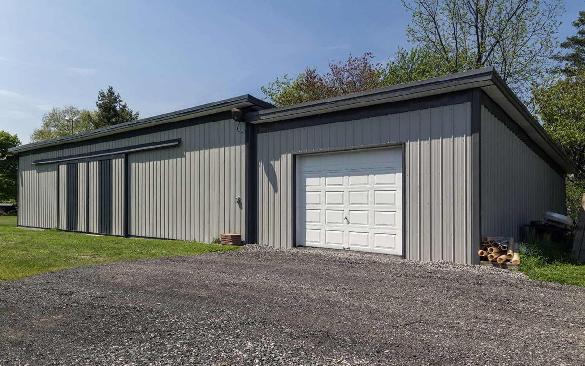 A large grey  metal barn with attached garage 