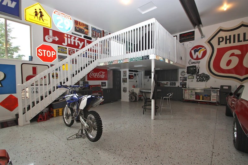 interior of man cave pole barn garage with a dirt bike, car and loft stairs