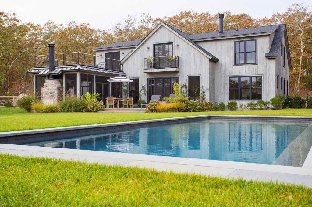 big pole barn home in grey color with huge lawn and pool area