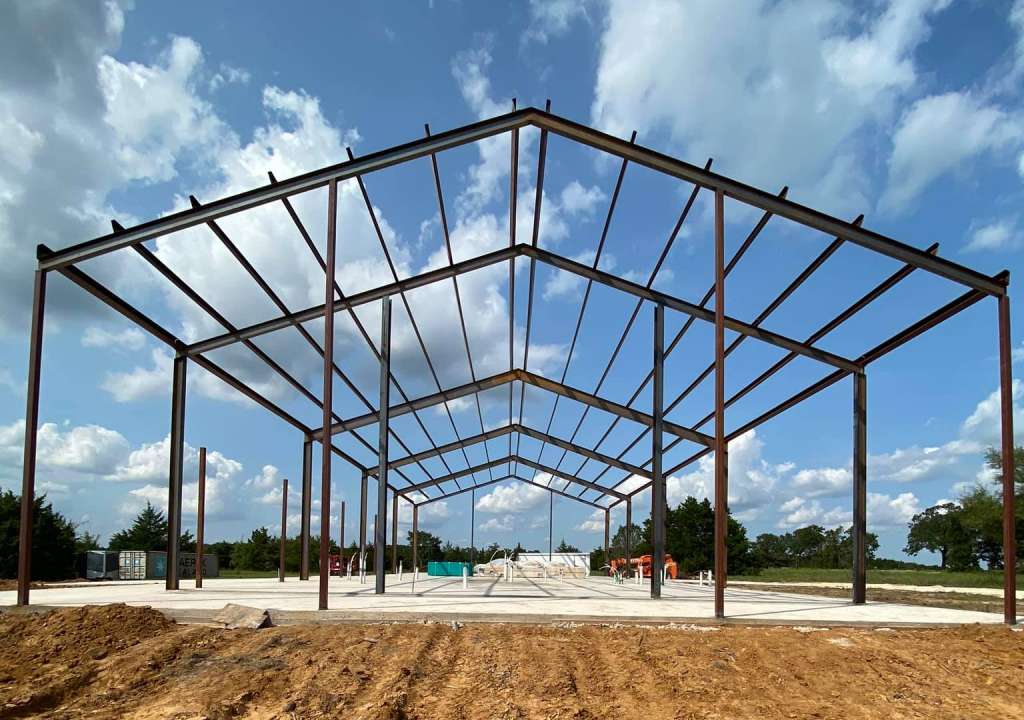 Metal frame of a one-story pole barn building on cocncrete slab.