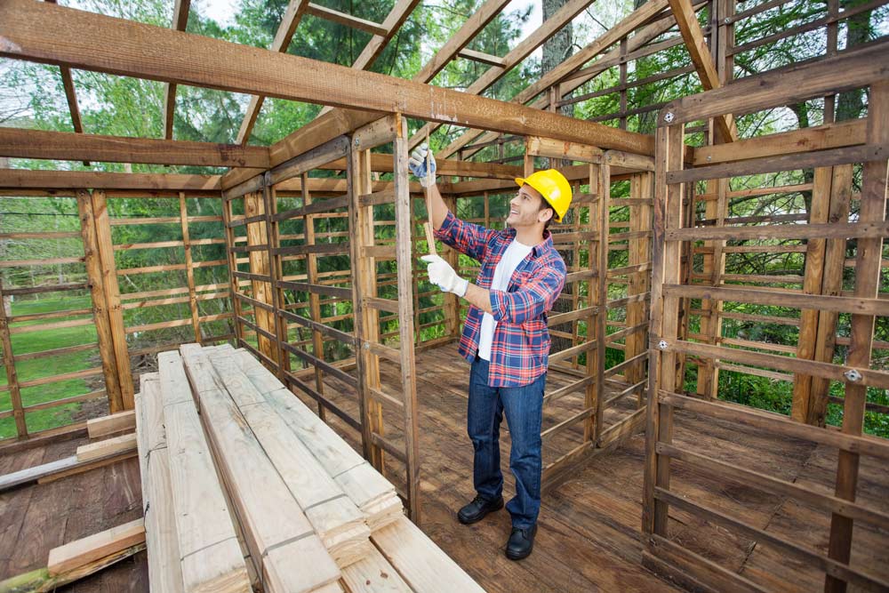 a man with safety helmet inspecting timber frame of pole barn home kit