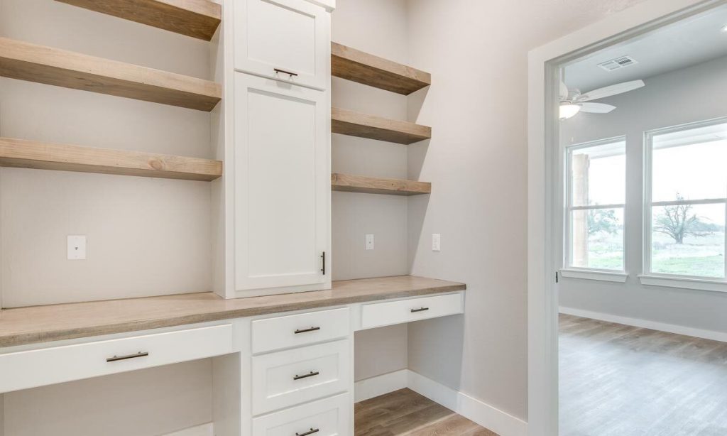 Walk-in closet of a regular bedroom with white shelves and drawers.