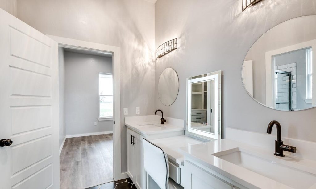 Bathroom with 2 sinks with round mirrors. and a desk with stool and light mirror.
