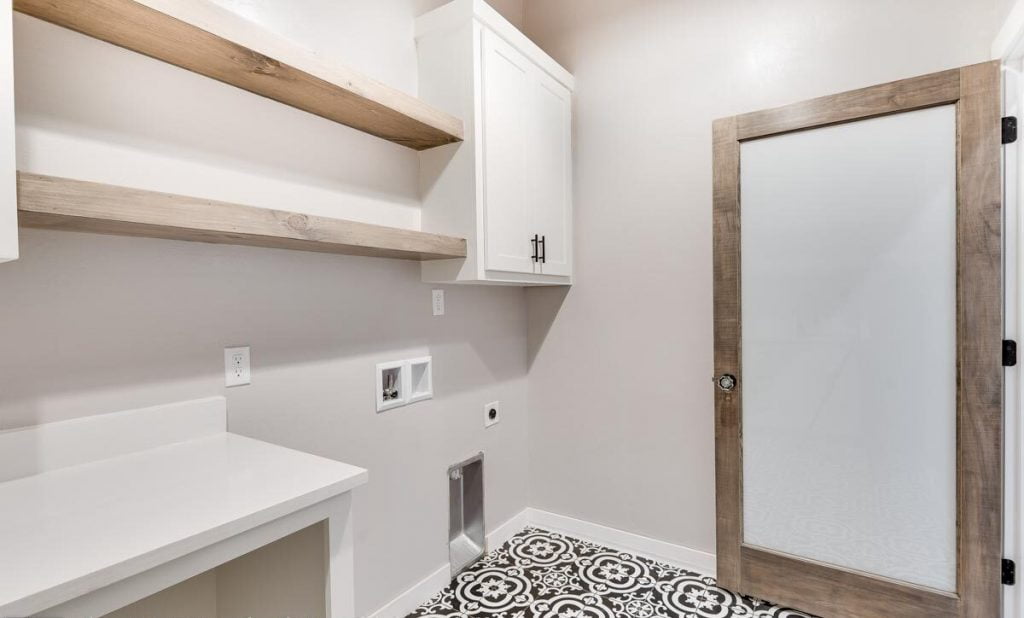 View of the laundry room with countertops, shelves and cabinets.