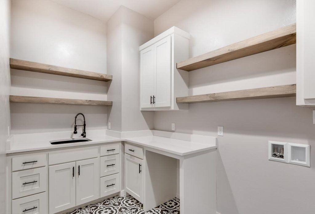 View from a different angle of the laundry room with white countertops, shelves and cabinets.
