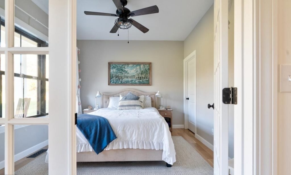 Bedroom with a white platform bed mounted artwork, and a ceiling fan.