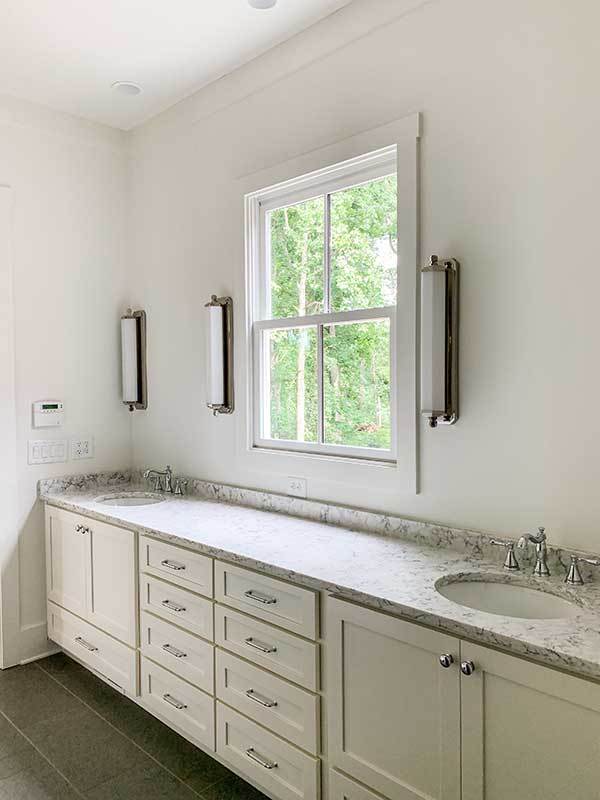 Bathroom marble countertops with sink and wall mounted lights.
