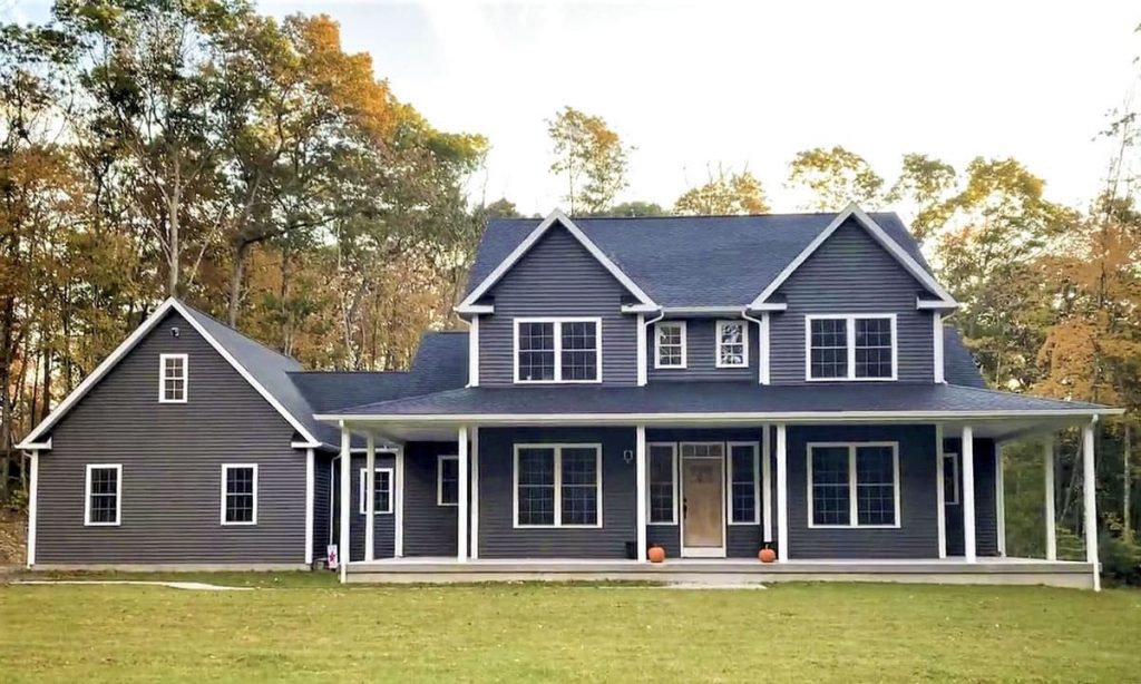 Front view of the traditional country home in a dark color scheme and white trim.