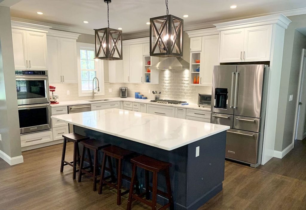 L-shaped kitchen equipped with an island with an eating area for 4-stools, white cabinets and ceiling lights.