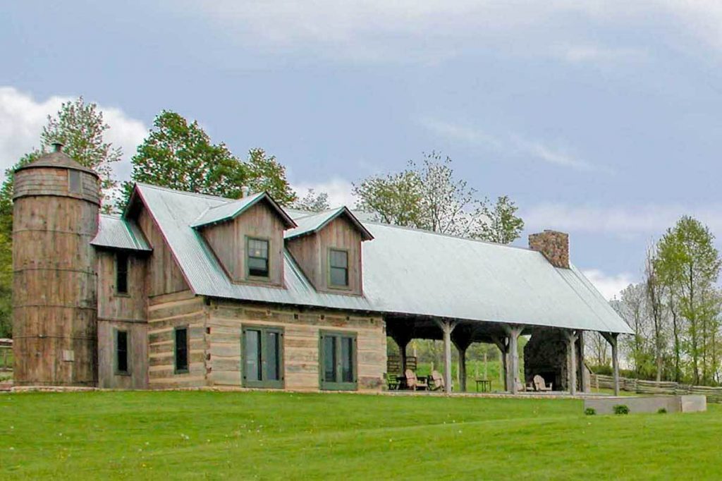 Front view of the Barndominium, showcasing its rustic design, the silo encasing the staircase, and the grand pavilion on the right side.
