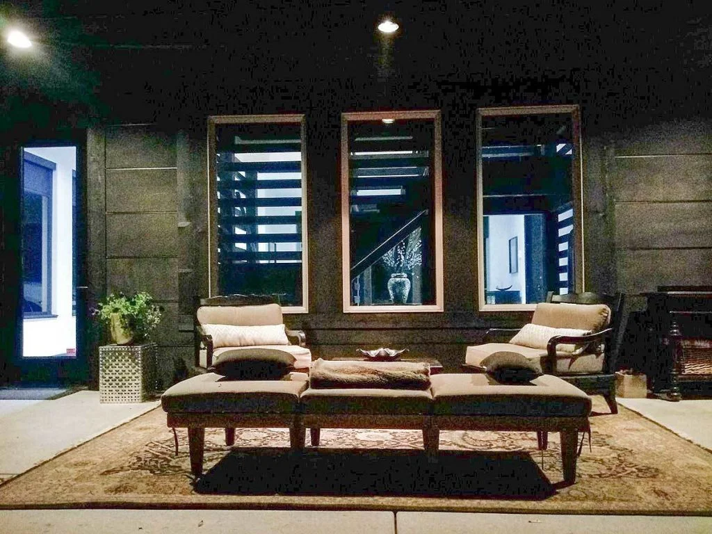 View of the covered porch showing cushioned armchairs and a rectangular sofa