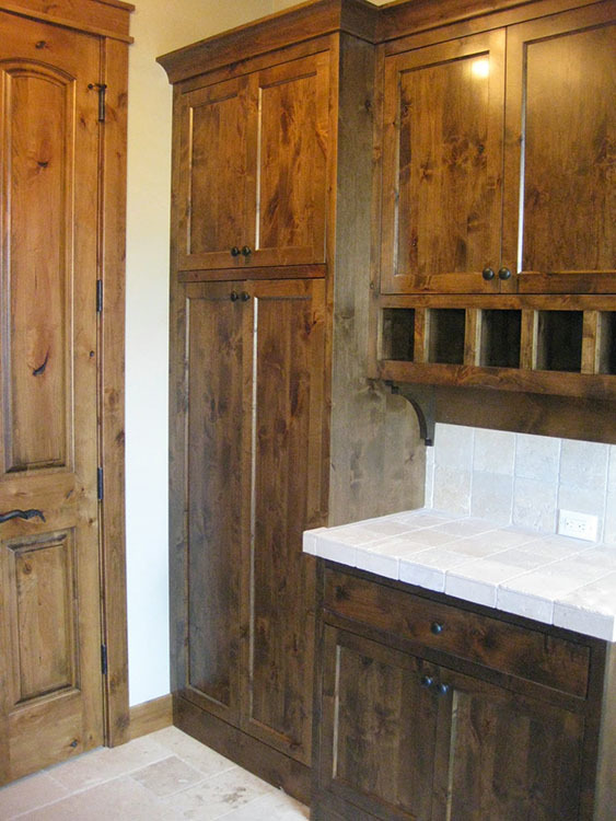 The mudroom shows white marble countertops, wooden cabinets, and a wooden door.
