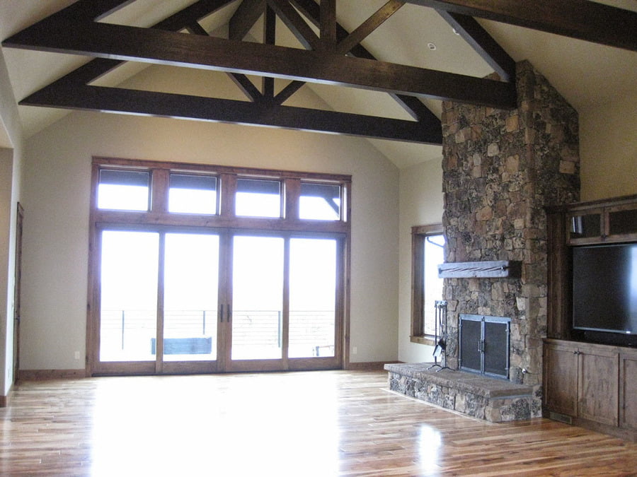 The living room shows a natural stone wall fireplace, a cabinet on the side, and a sliding glass door.