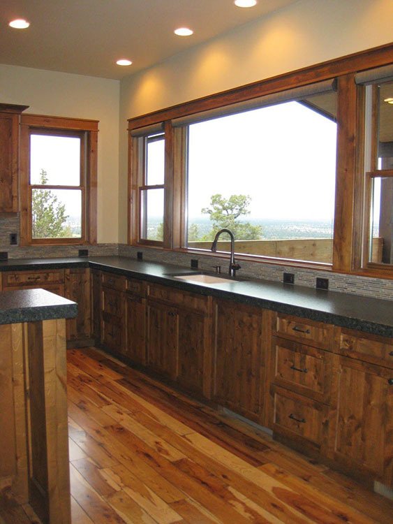 The kitchen shows marble countertops, wooden cabinets, and a wall window showing beautiful scenery.