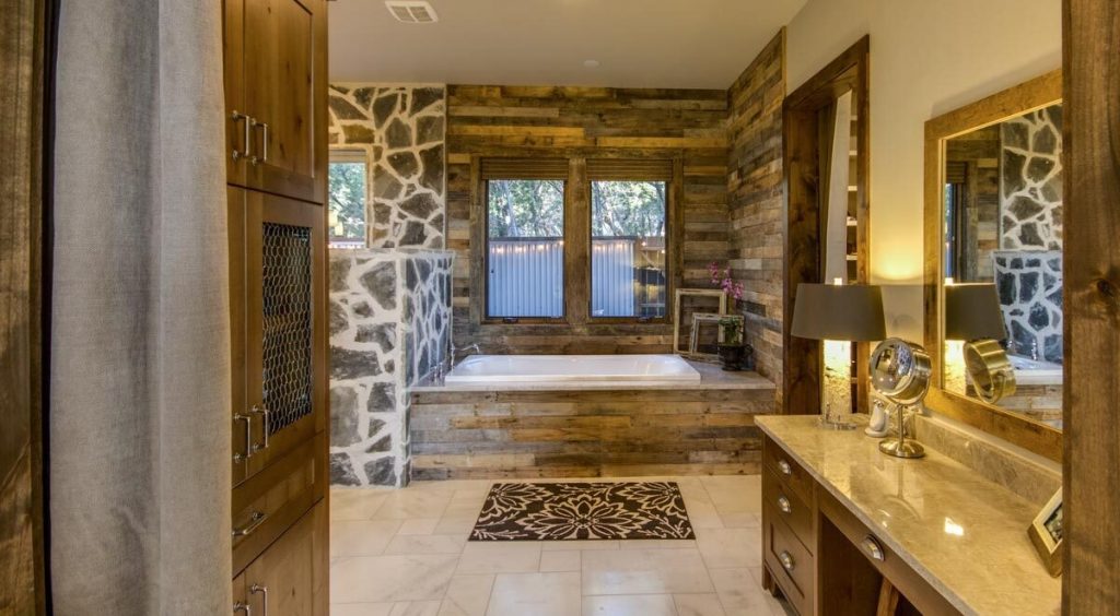 The master's bathroom provides the country house vibe with its marble countertop, wooden cabinet, and stone and wood wall