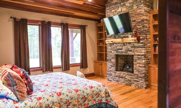 Master suite with stone fireplace and mounted tv.