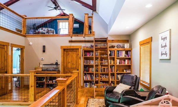 Loft furnished with armchairs and wooden bookshelves.