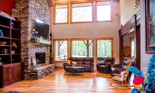 Family room with a stone fireplace, furnished with leather armchairs, sofa, and mounted tv.
