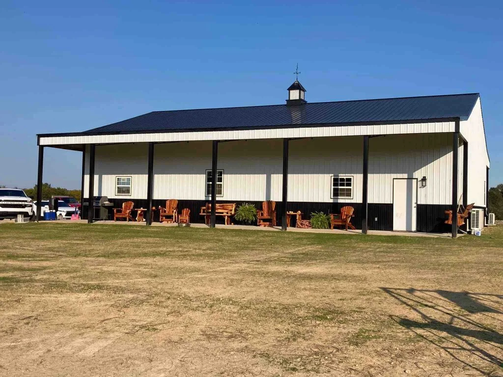 40 x 60 white barndominium aka metal building home with a front porch and dark blue roof